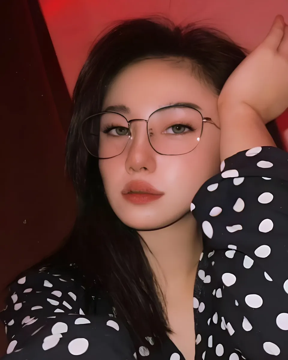 Justine Ponteras wearing glasses and polka dot top in red-lit setting