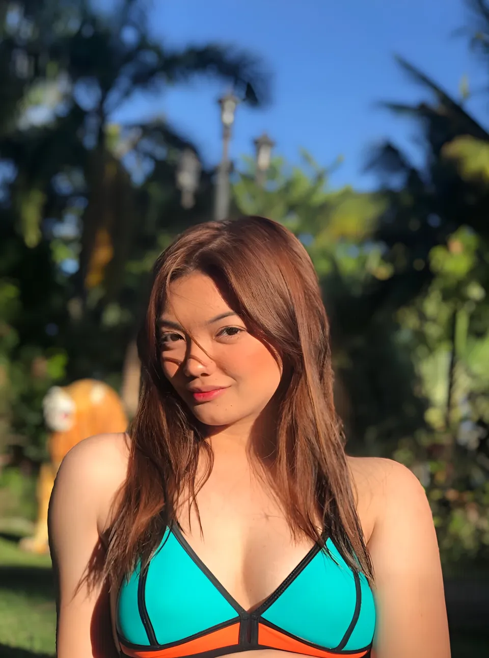 Kath Mandal in teal and orange bikini top outdoors with palm trees