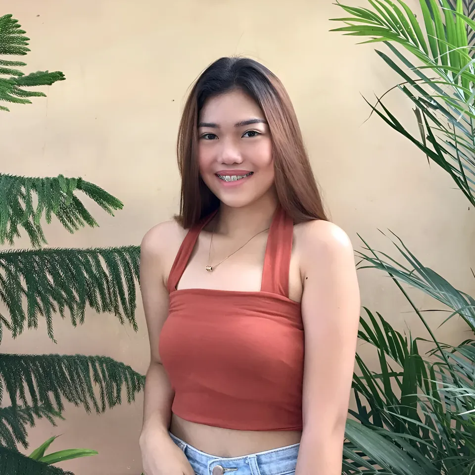 Katrina Alexis in orange crop top standing with plants behind her