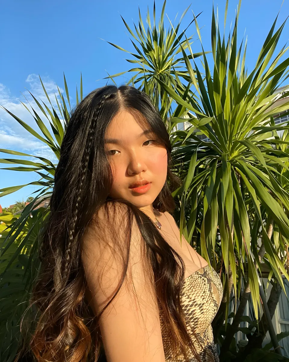 King Nicole in snake print top poses outdoors with palm plants