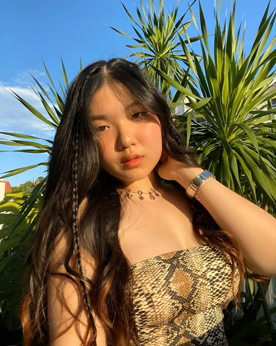 King Nicole in snake print top poses outdoors with palm plants