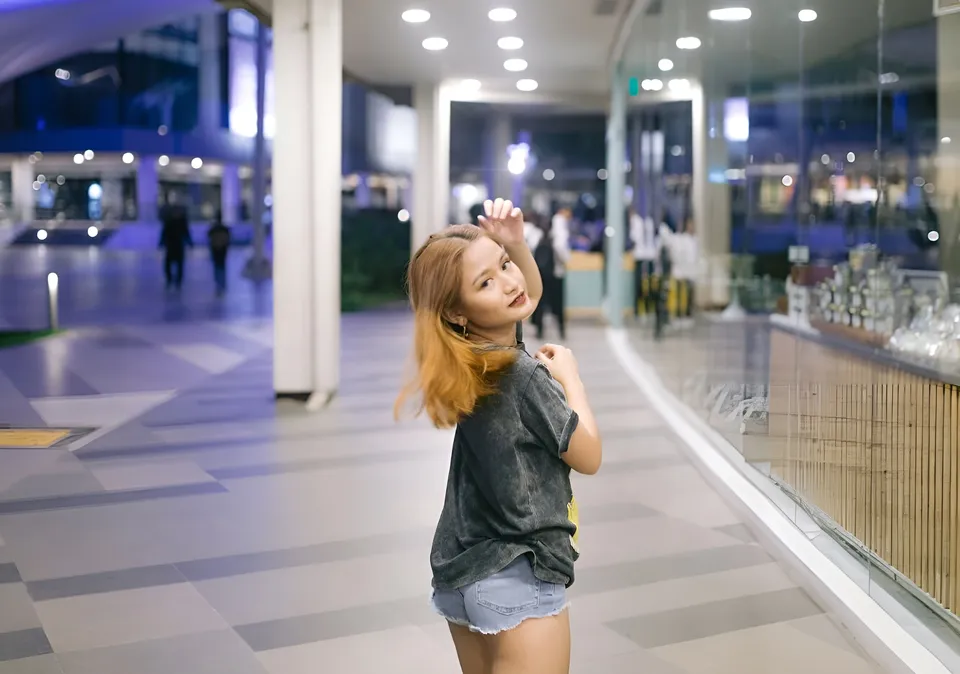 Krysta Matias in dark top and denim shorts standing in mall corridor