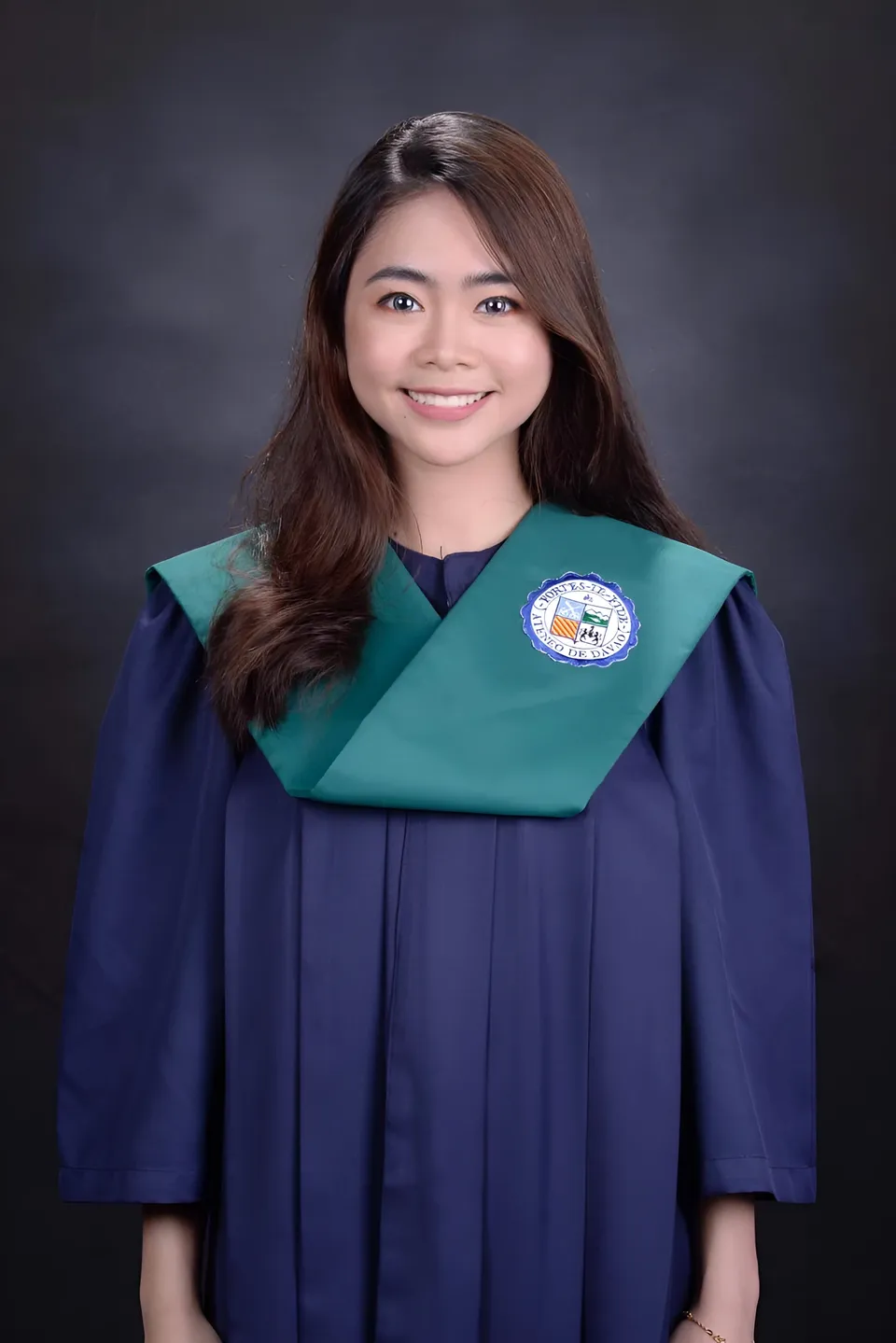 Kyla Auza wearing a dark gown with a green collar poses against a dark background