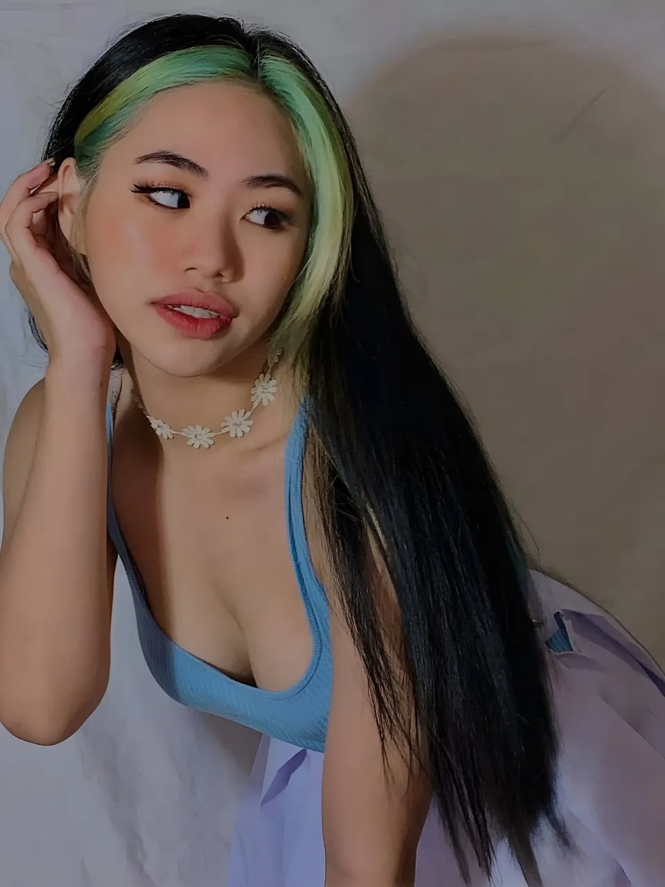 Kylene Santos with green and black hair wearing blue top and floral necklace