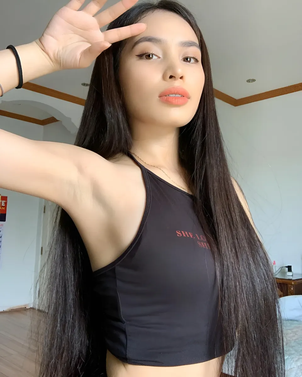 Lhyn Ampong wearing black crop top with arm raised indoors