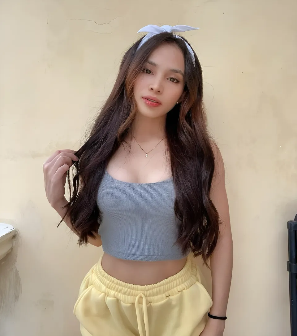 Lhyn Ampong wearing gray crop top and yellow pants, standing against wall