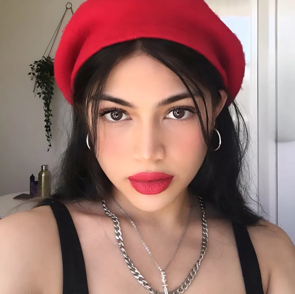 Lia Mae Vumbaca wearing red beret and black top in indoor setting