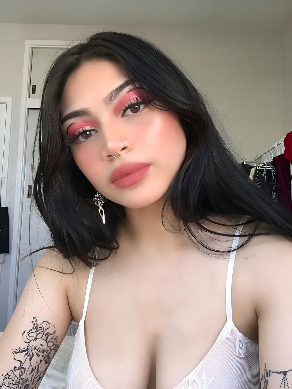 Lia Mae Vumbaca wearing white lace top with visible tattoos and earrings