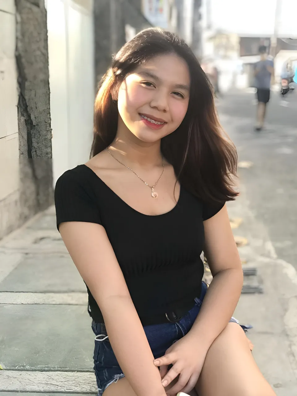 Love Dela Pe wearing black top and jeans sitting on steps outdoors