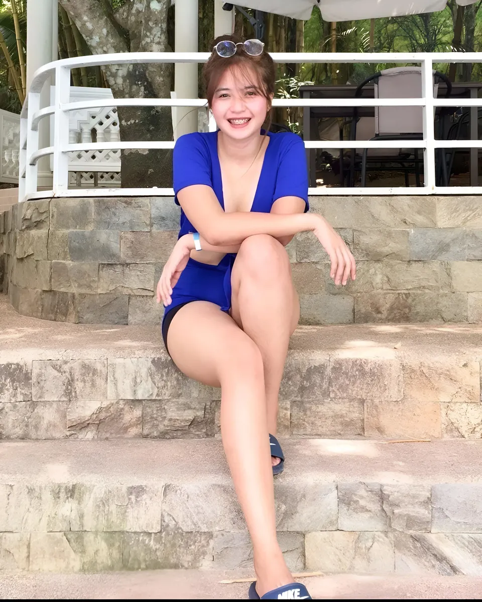 Mae Roxas in blue top sitting on stone steps outdoors