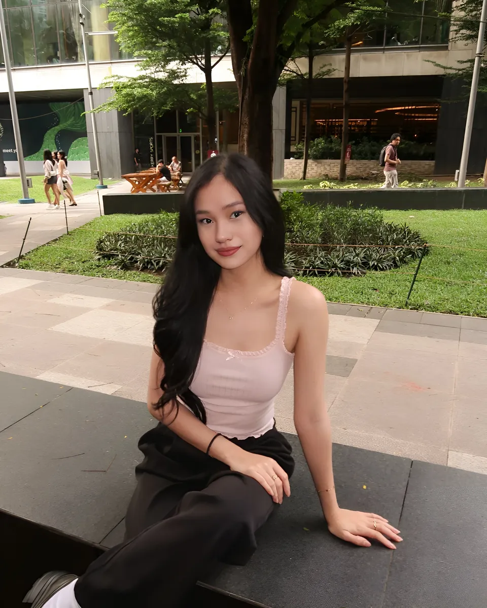Maeve Linden in pink top sits on bench outdoors
