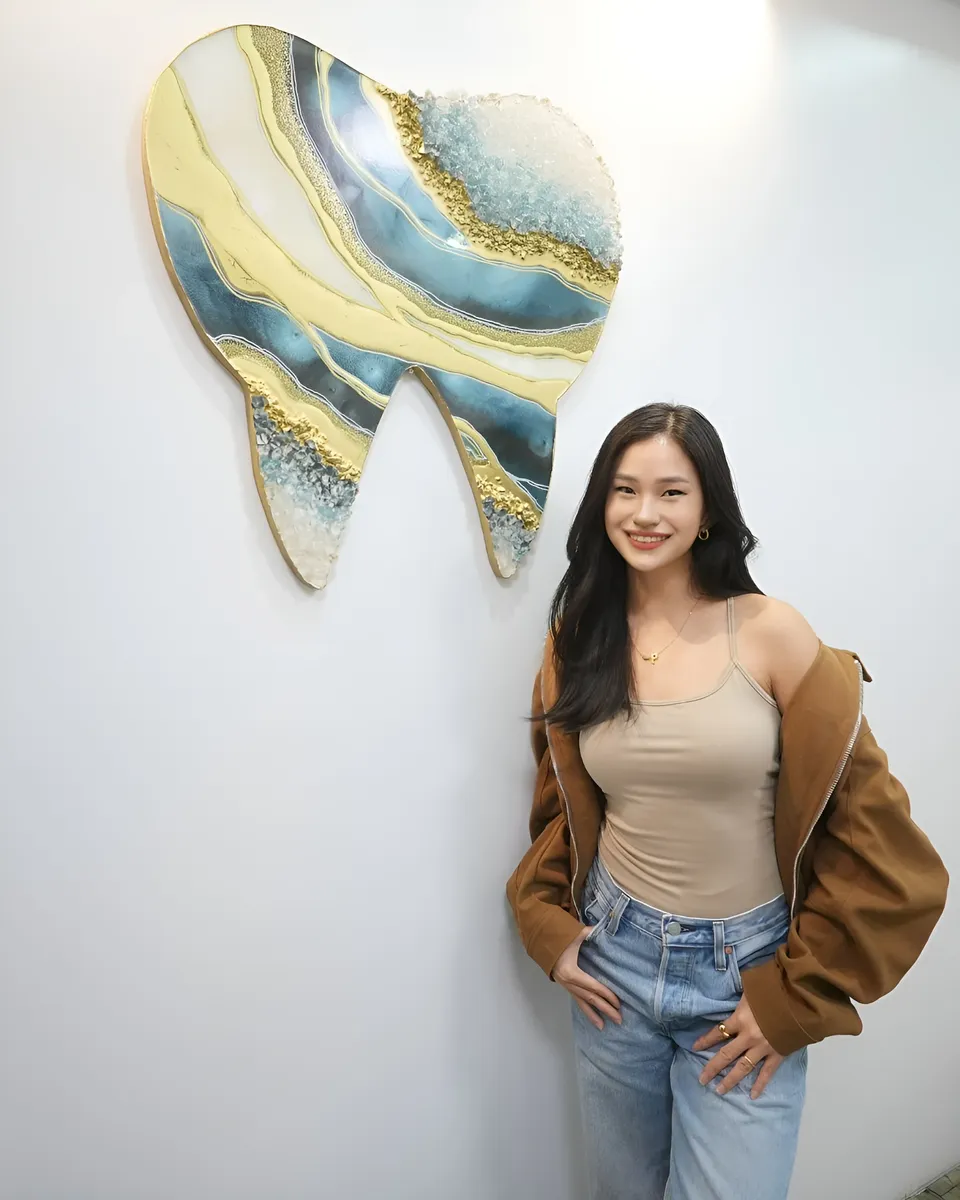 Maeve Linden standing beside large tooth-shaped wall art