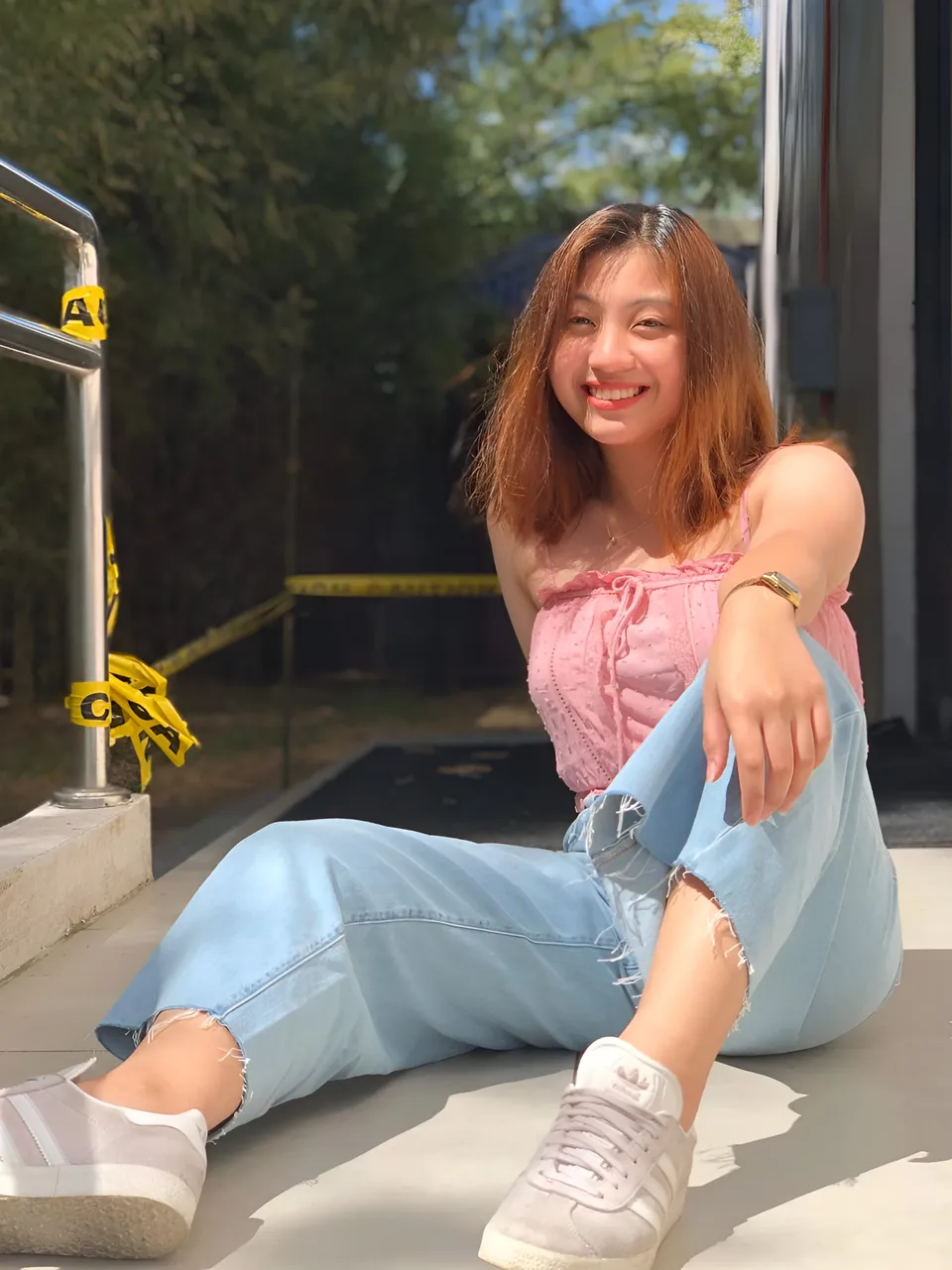 Mariah Protacio in pink top and light blue jeans sitting outdoors