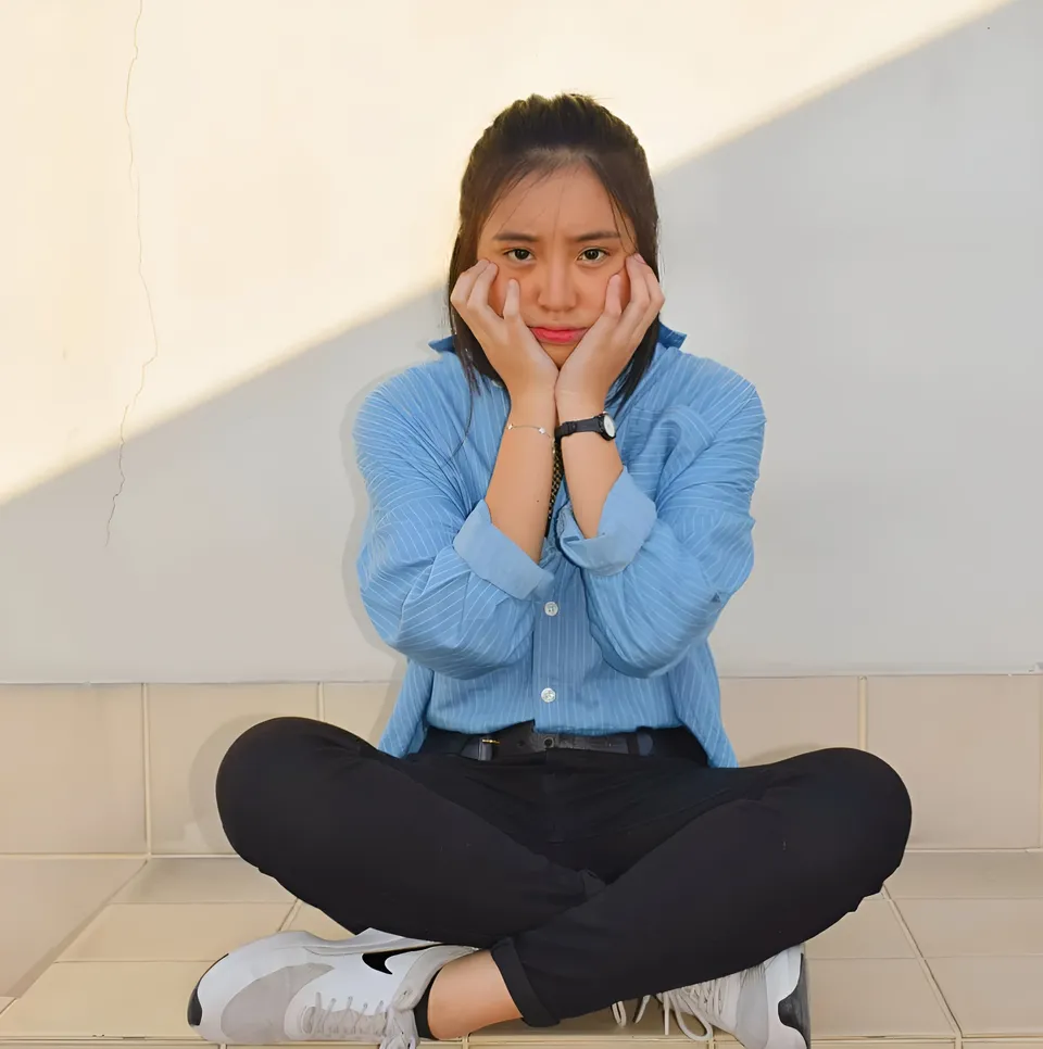 Marsell Cali sitting cross-legged on tiled floor with hands on cheeks