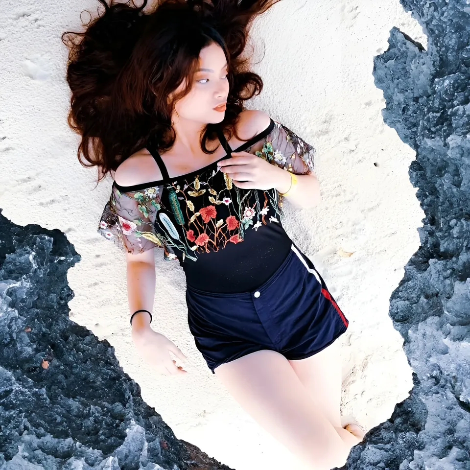 Mary Therese Rizon lying on beach in embroidered top and shorts