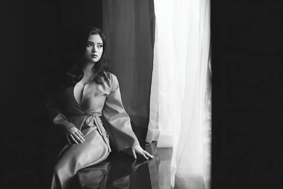 Mary Therese Rizon in robe seated by window with sheer curtains