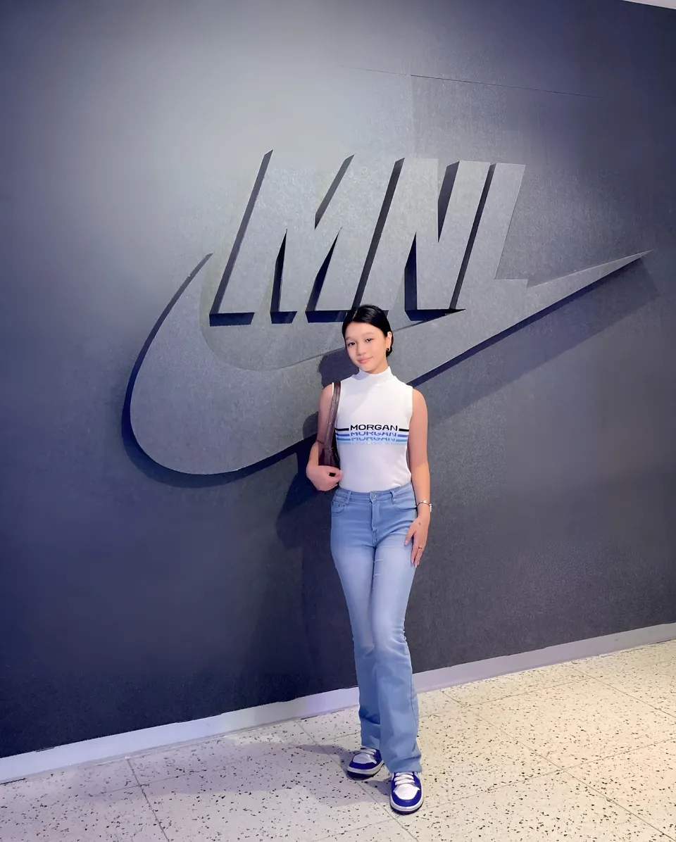 Maryshel Monroe standing in front of large logo on dark wall