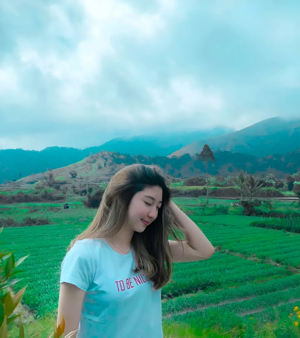 Michelle Arden in light blue top standing in green field with mountains