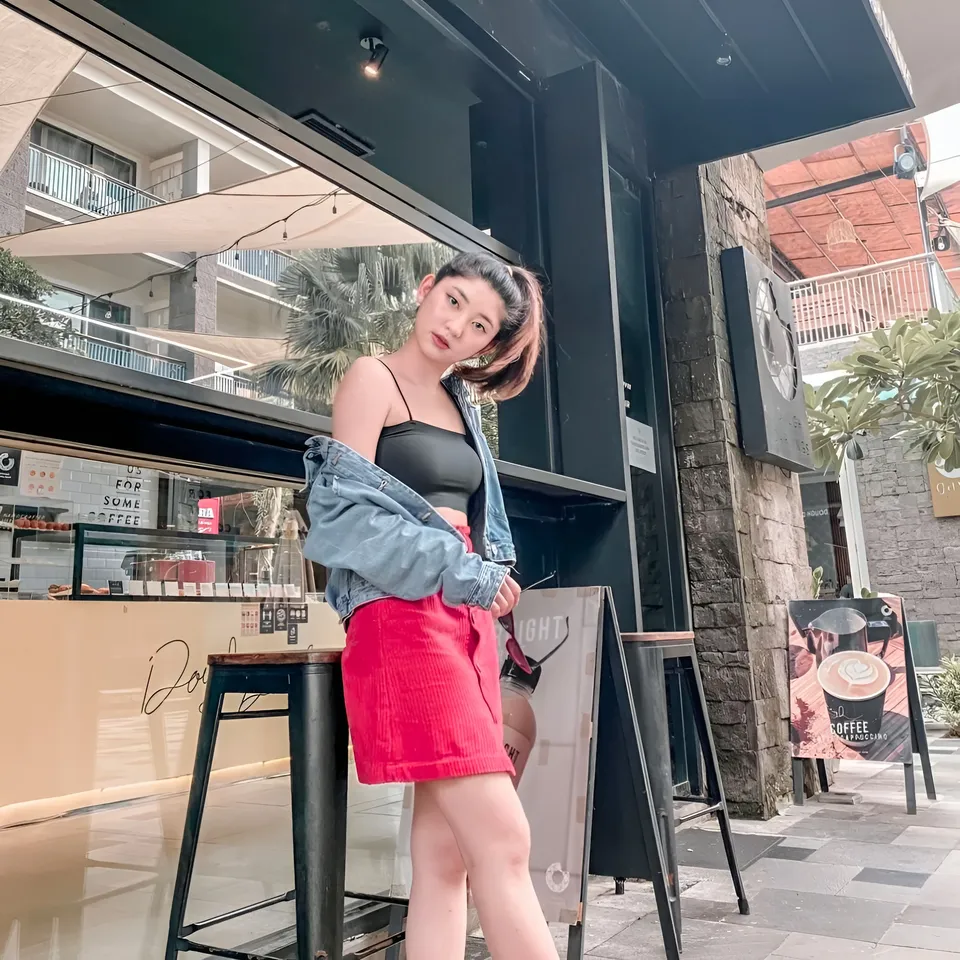 Michelle Arden in red skirt and denim jacket standing outside café