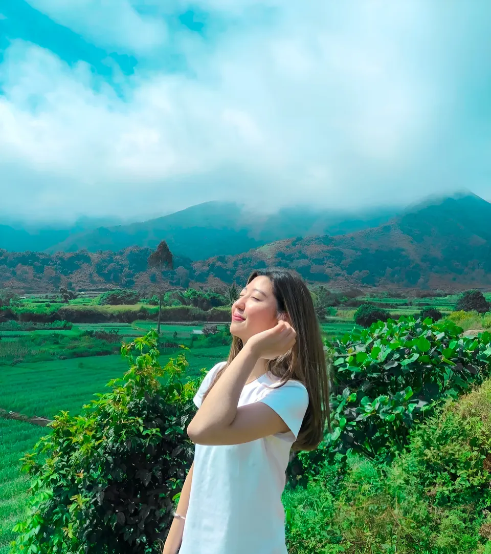Michelle Arden in white top standing outdoors with green hills and mountains