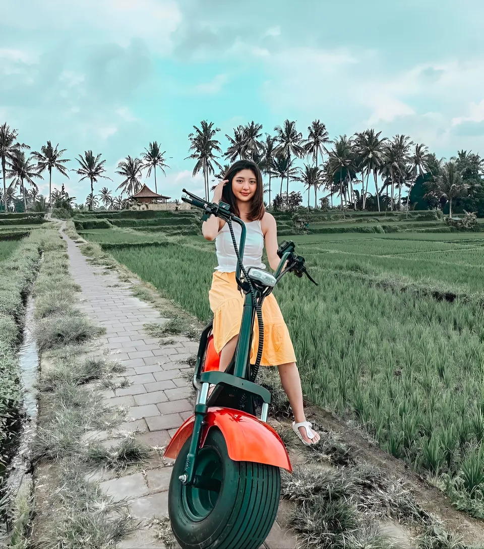 Michelle Arden standing with electric scooter on path beside rice fields
