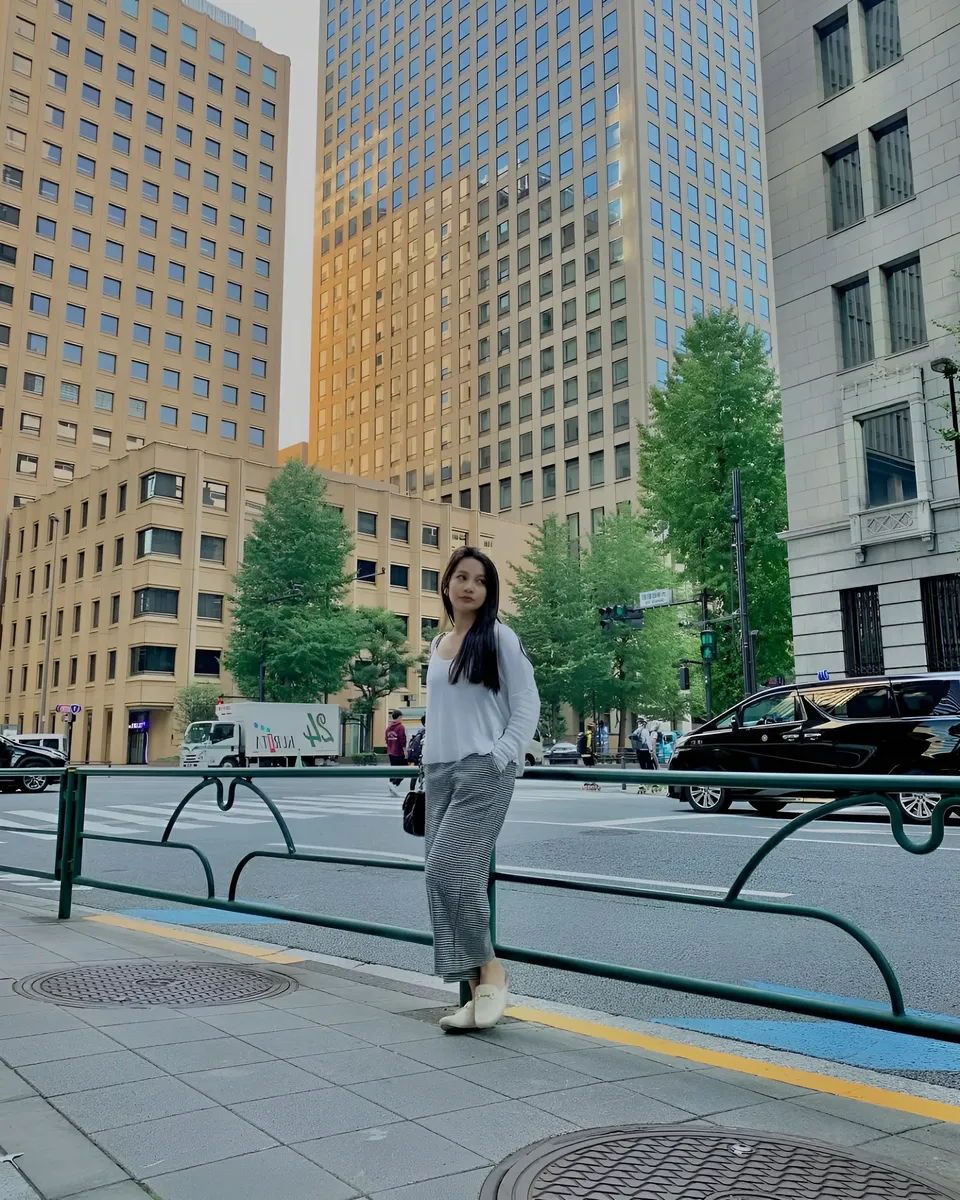 Mikay Alexis standing on sidewalk beside green railing