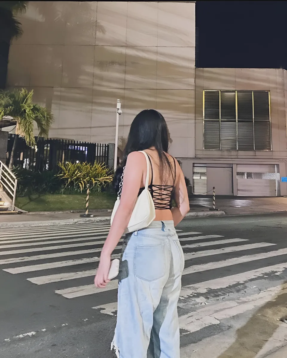 Mira Collins standing on street crossing at night with building in background