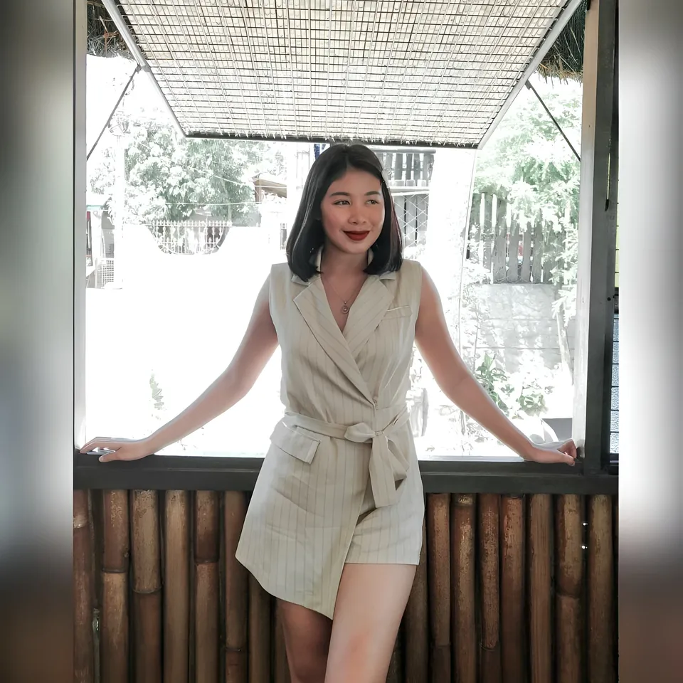 Moraya Ong wearing a beige striped outfit poses beside a bamboo railing