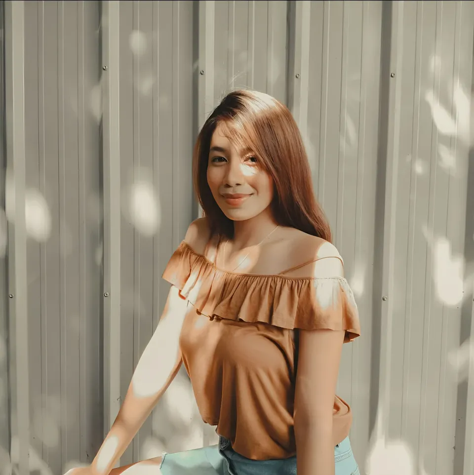 Moraya Ong in brown top seated against corrugated metal wall