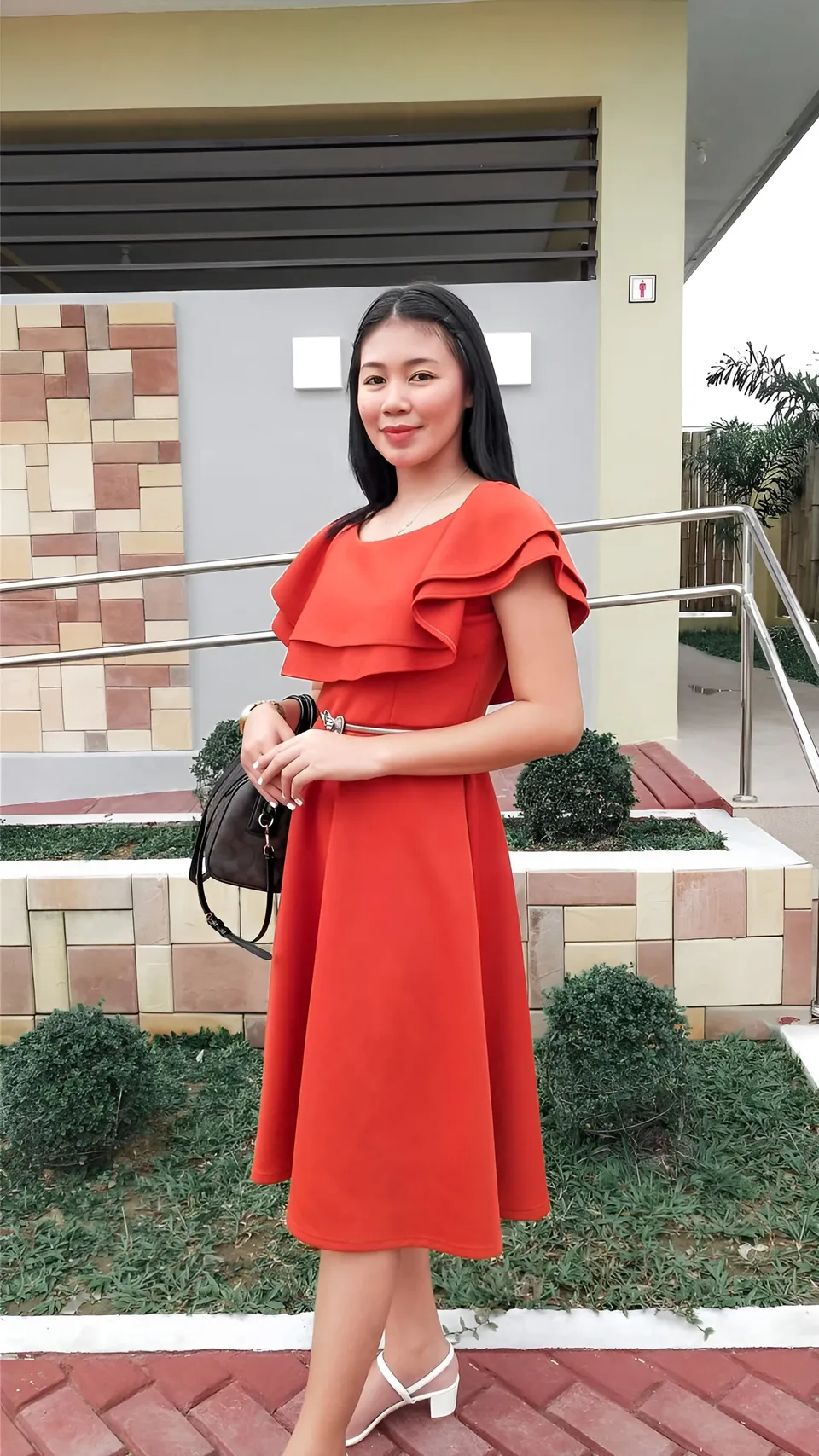 Moraya Ong in red dress standing outdoors on brick path