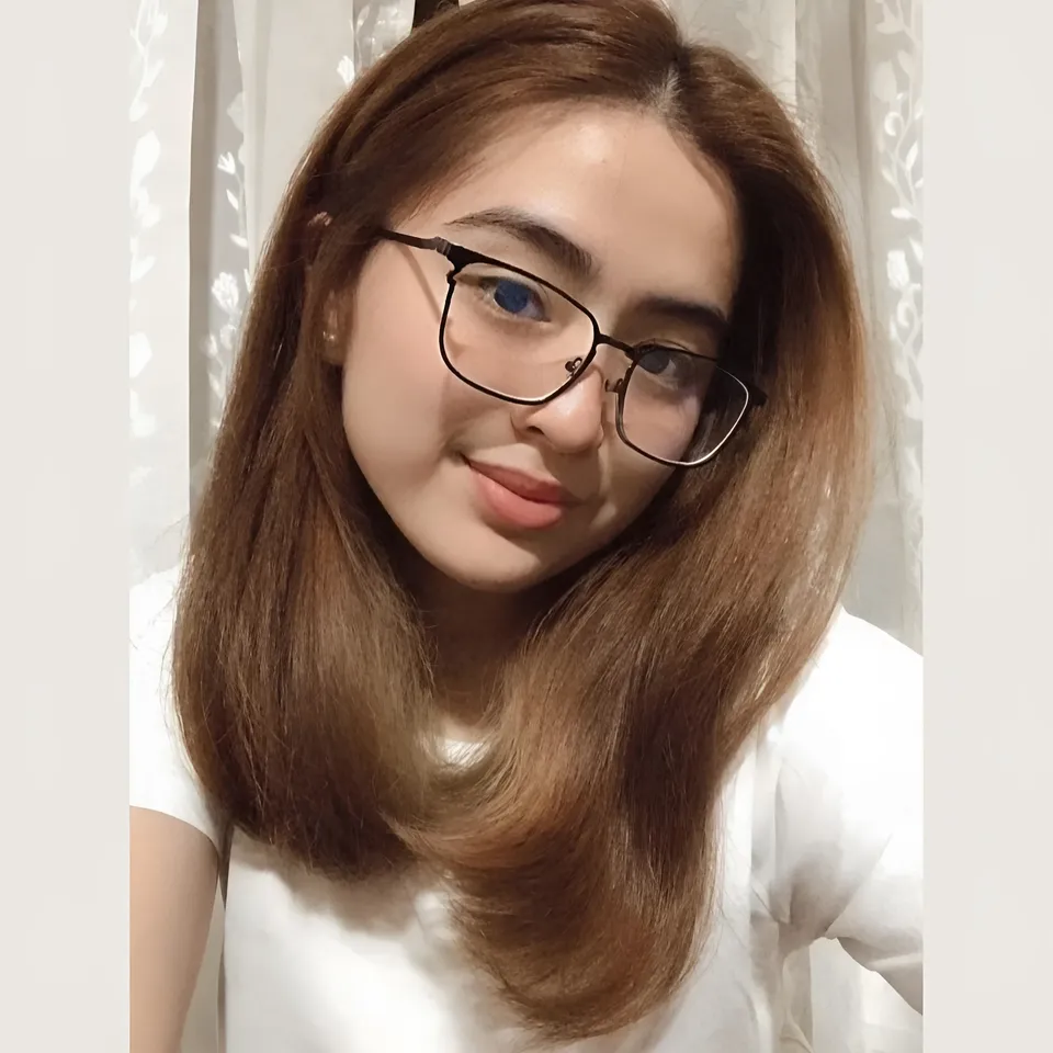 Pamela Tanbua wearing glasses and white top in front of curtain