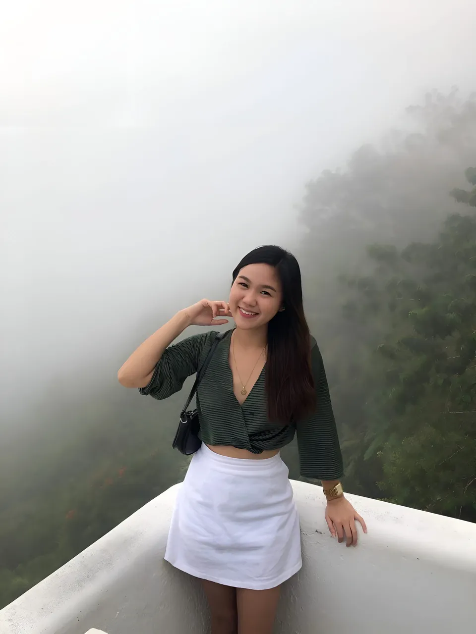 Pia Gonzales in striped top and white skirt stands on foggy overlook
