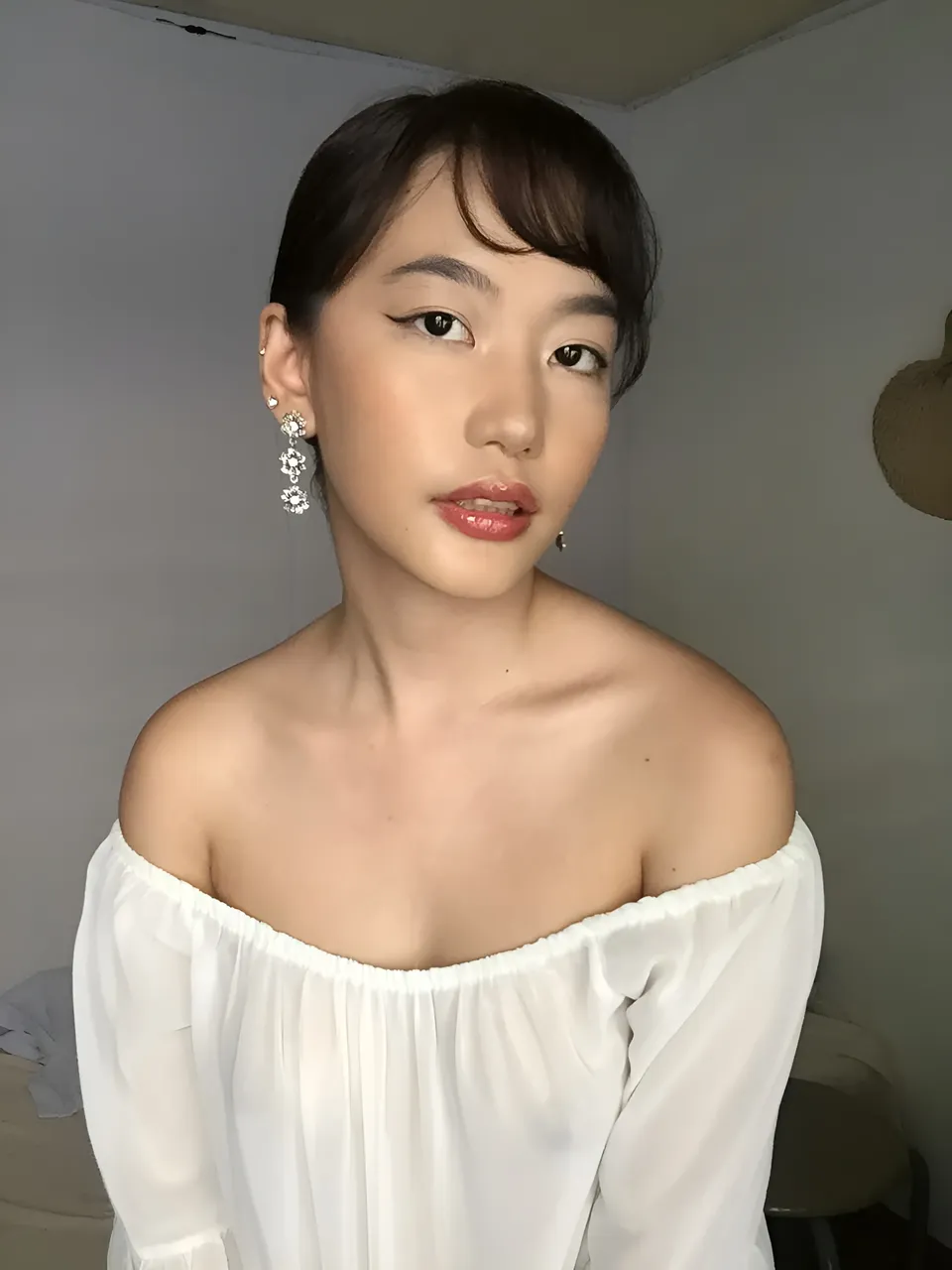 Ramoana Sinclair in white off-shoulder top with dangling earrings