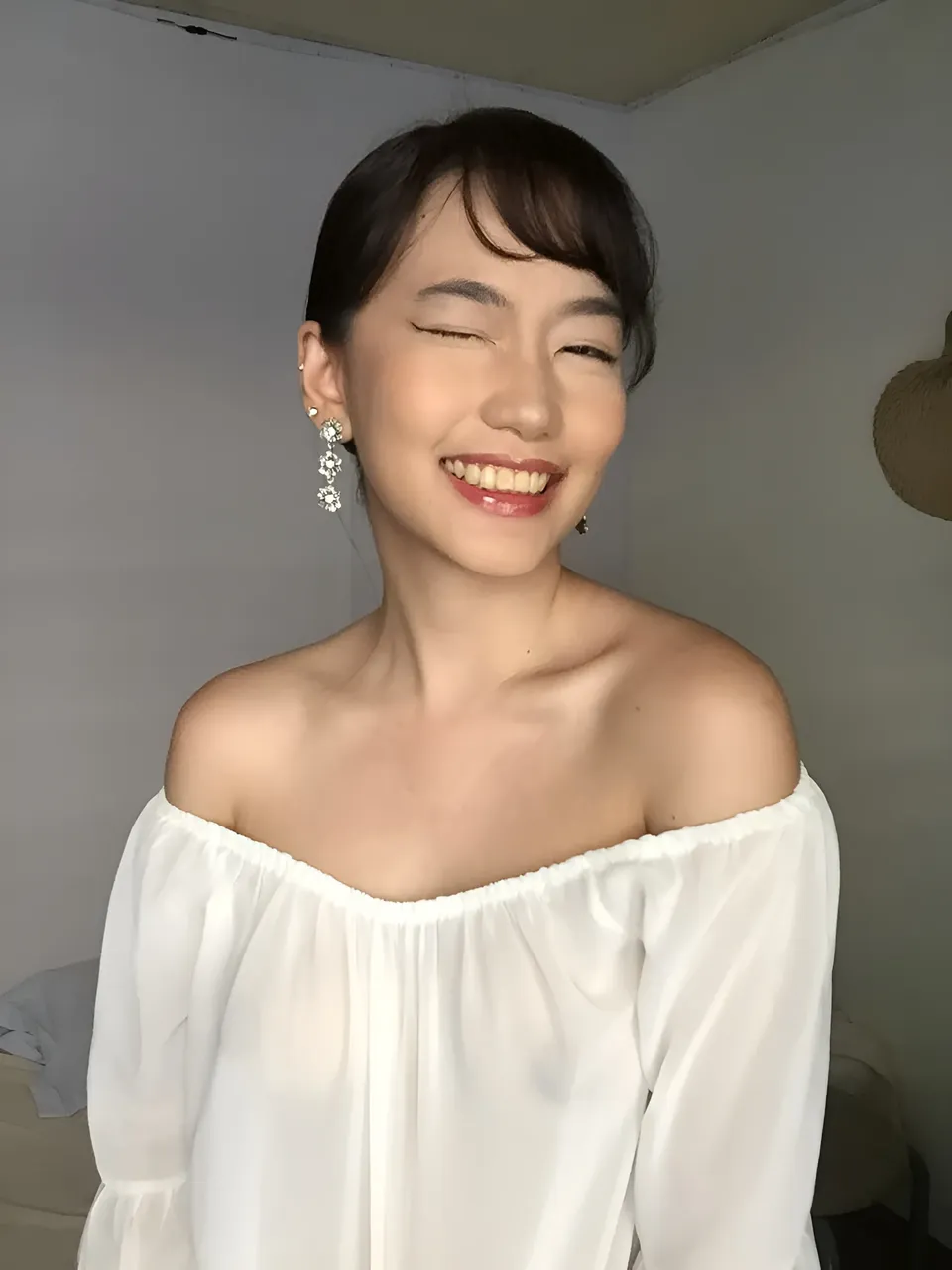 Ramoana Sinclair smiling with eyes closed wearing white off-shoulder top