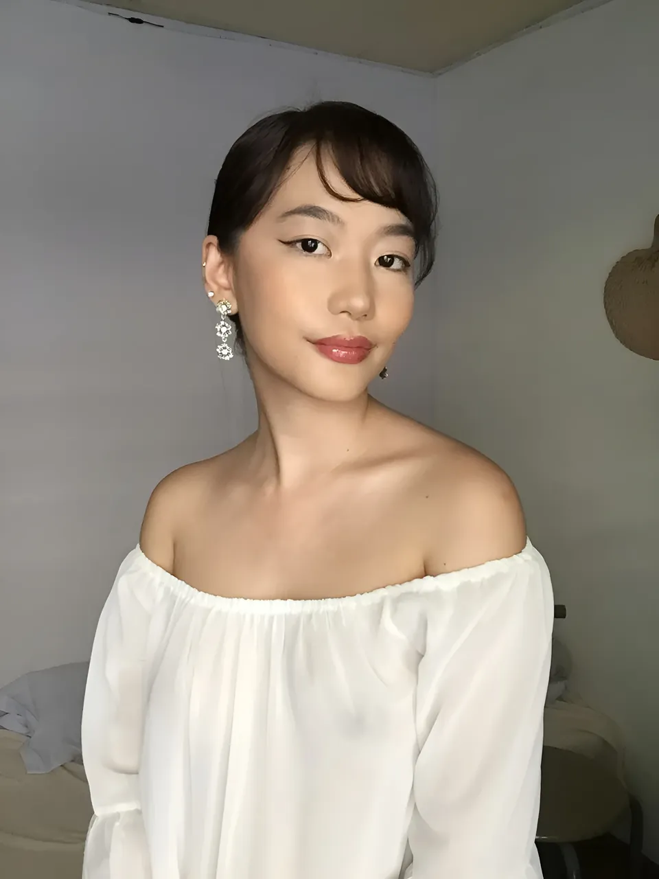 Ramoana Sinclair in white off-shoulder top with dangling earrings