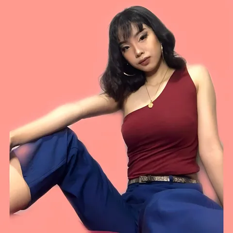 Rayen Portus wearing red top and blue pants seated against pink background