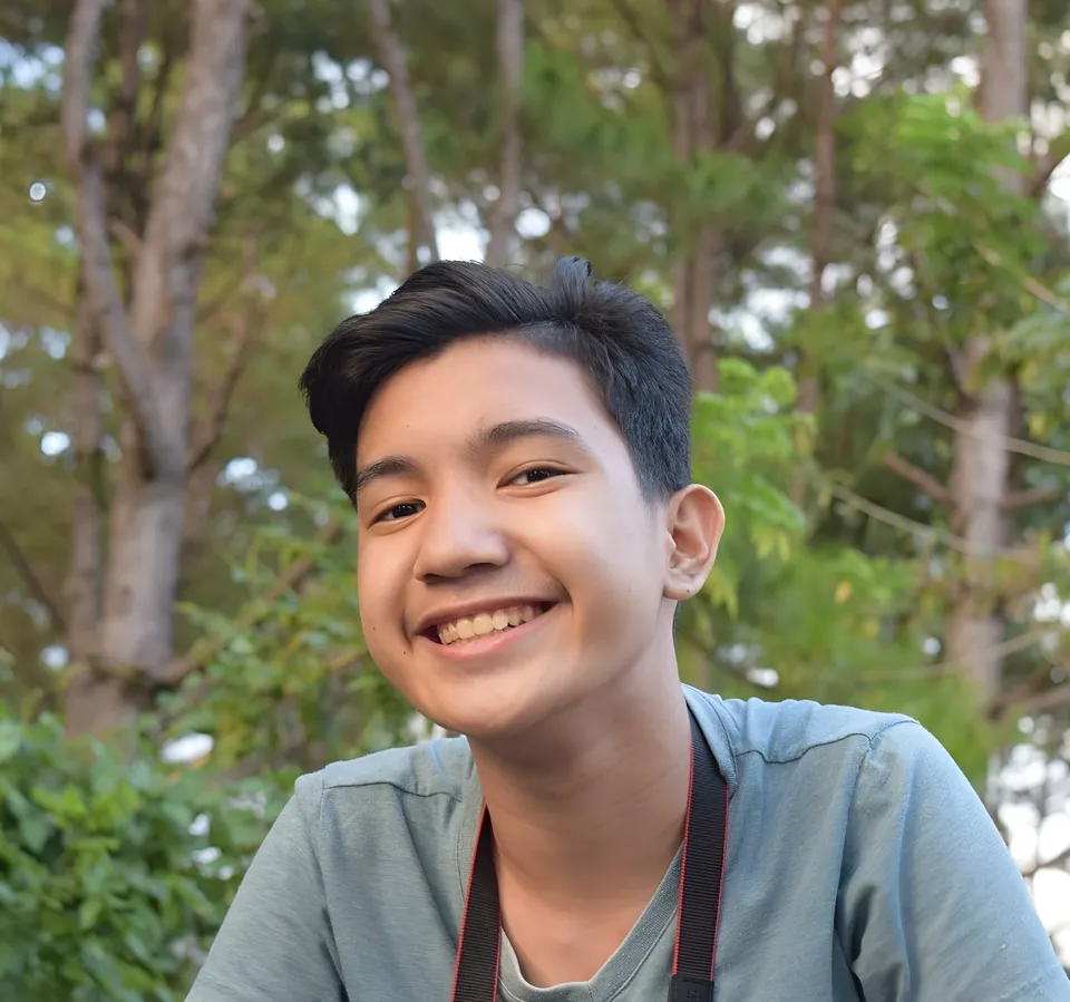 Rowella Sanchez smiling in blue shirt with camera strap outdoors