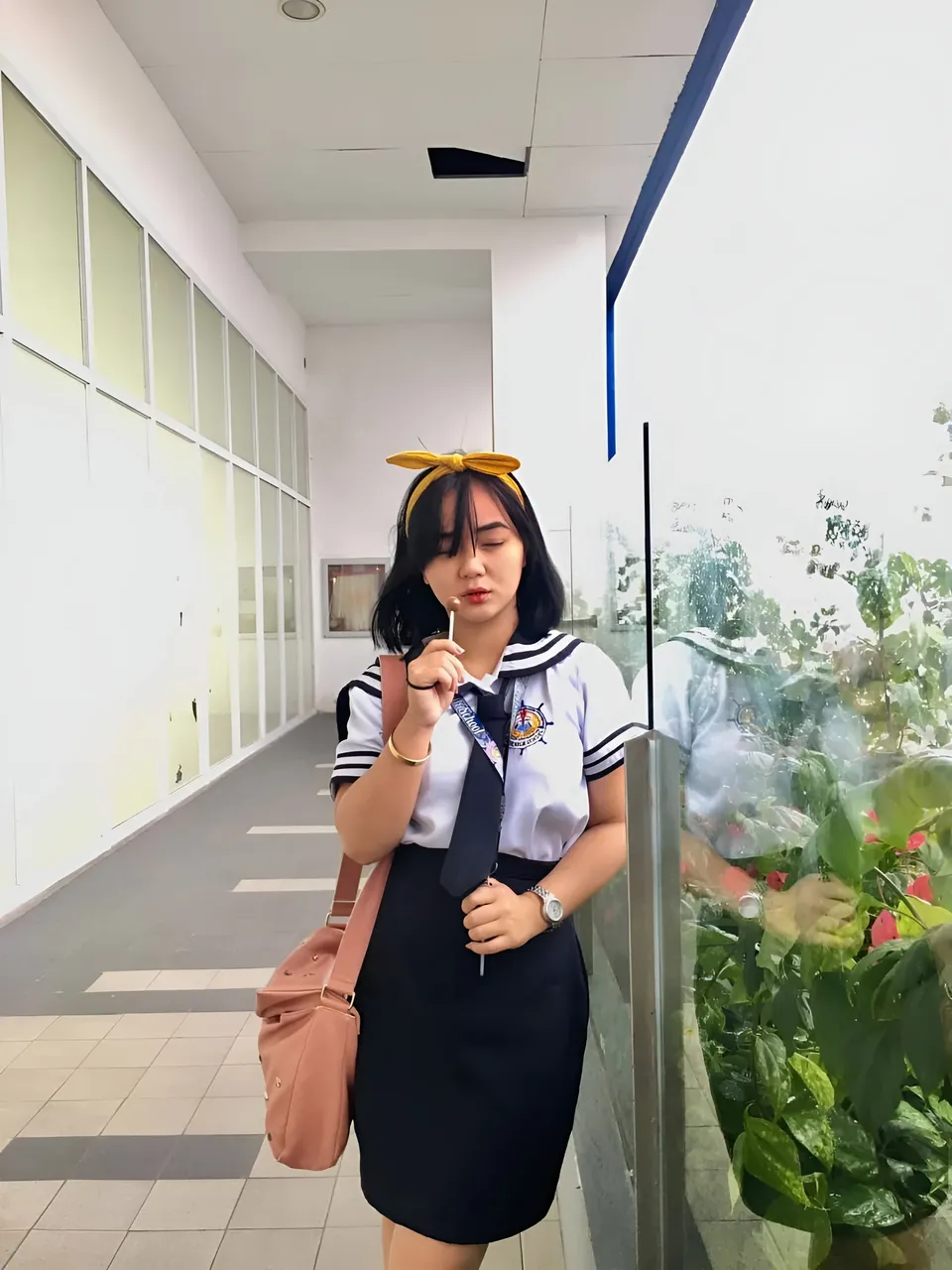Sakura Keyema wearing a navy skirt and light top poses beside corridor windows