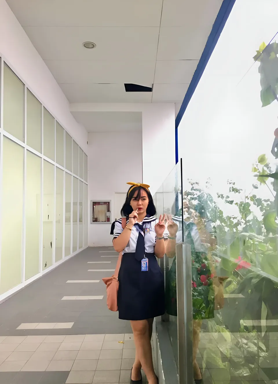 Sakura Keyema wearing a navy skirt and light top poses in a bright corridor