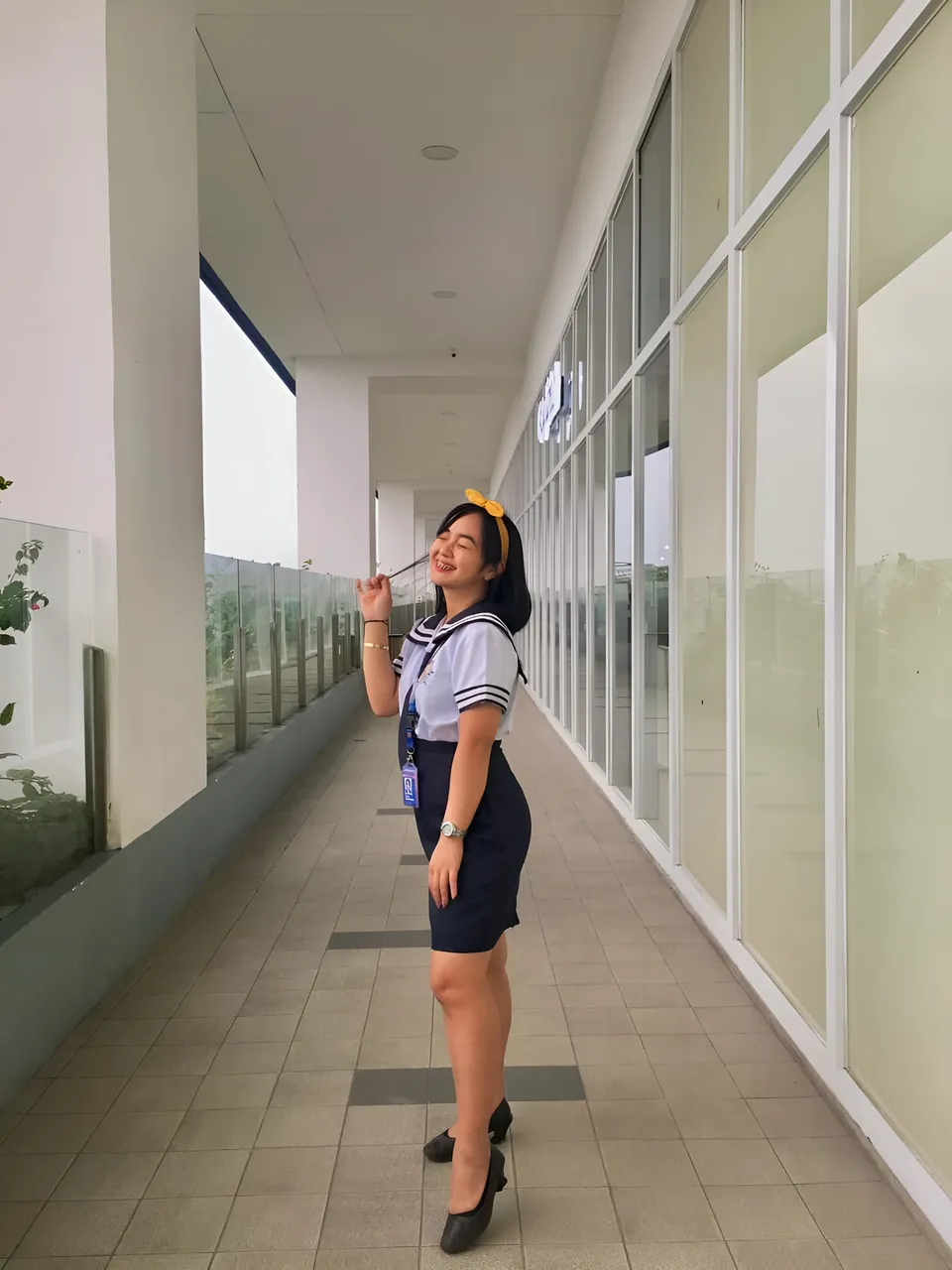 Sakura Keyema wearing a navy skirt and light top stands in a windowed corridor
