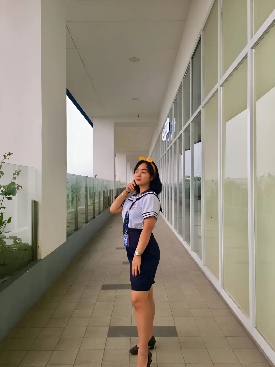 Sakura Keyema wearing a navy skirt and light top poses in a windowed corridor