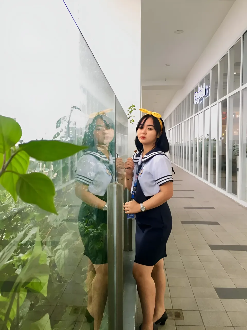 Sakura Keyema in navy skirt and white top stands beside glass wall