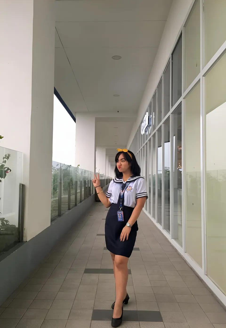 Sakura Keyema in sailor-style top and skirt standing in covered hallway