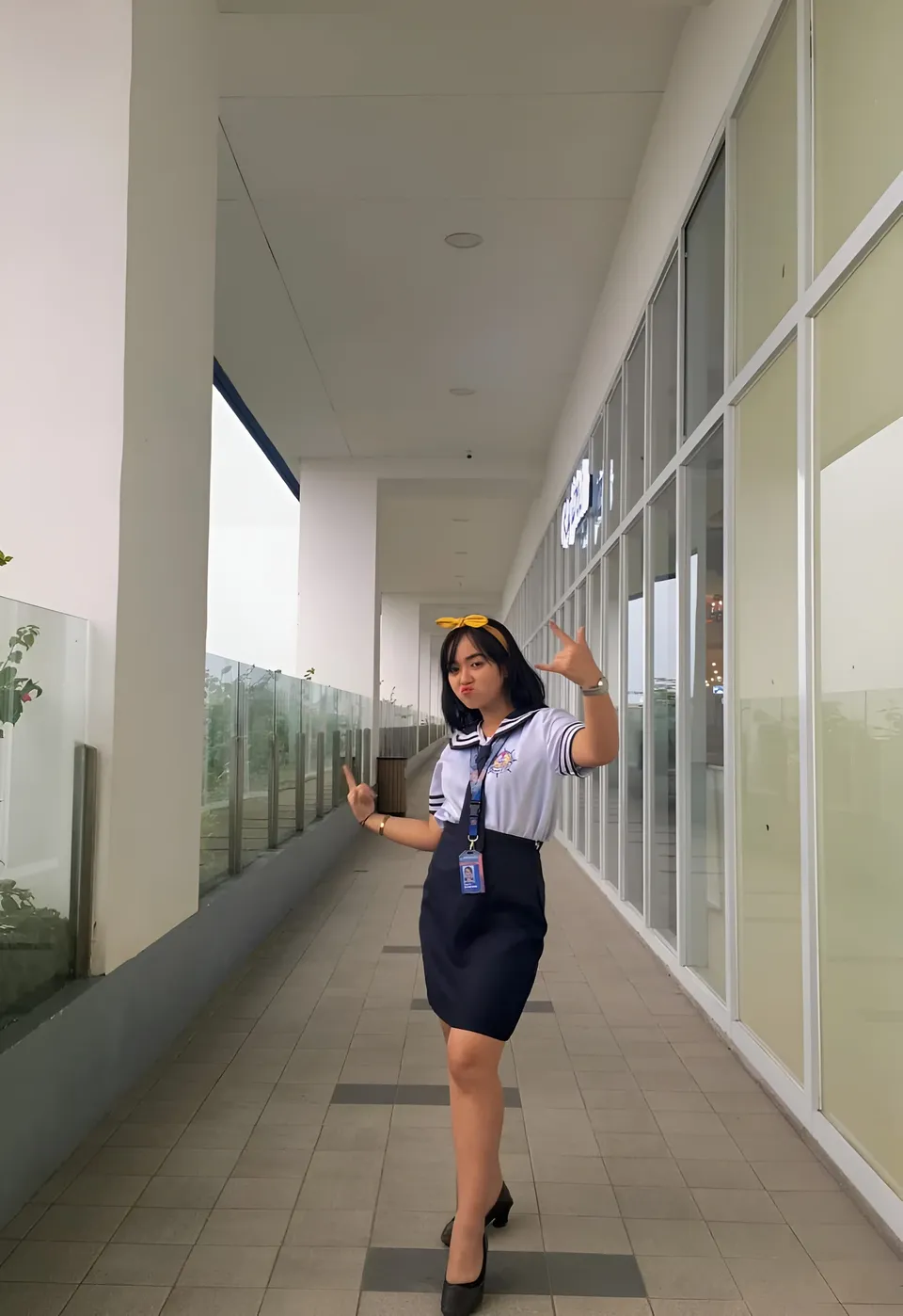 Sakura Keyema in navy skirt and sailor top posing in hallway