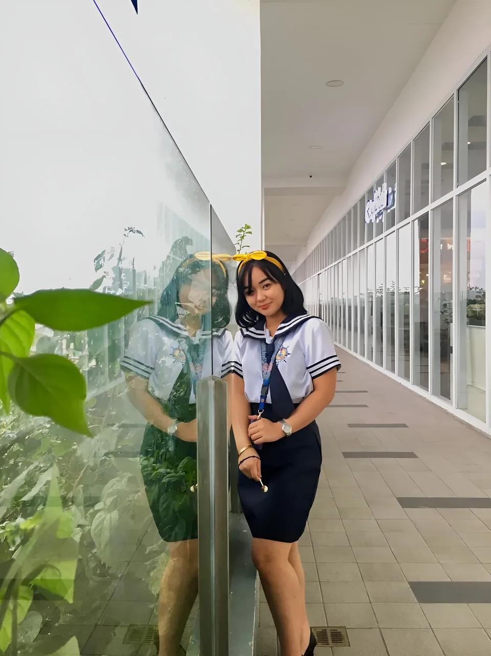Sakura Keyema wearing a navy skirt and light top poses in a windowed corridor