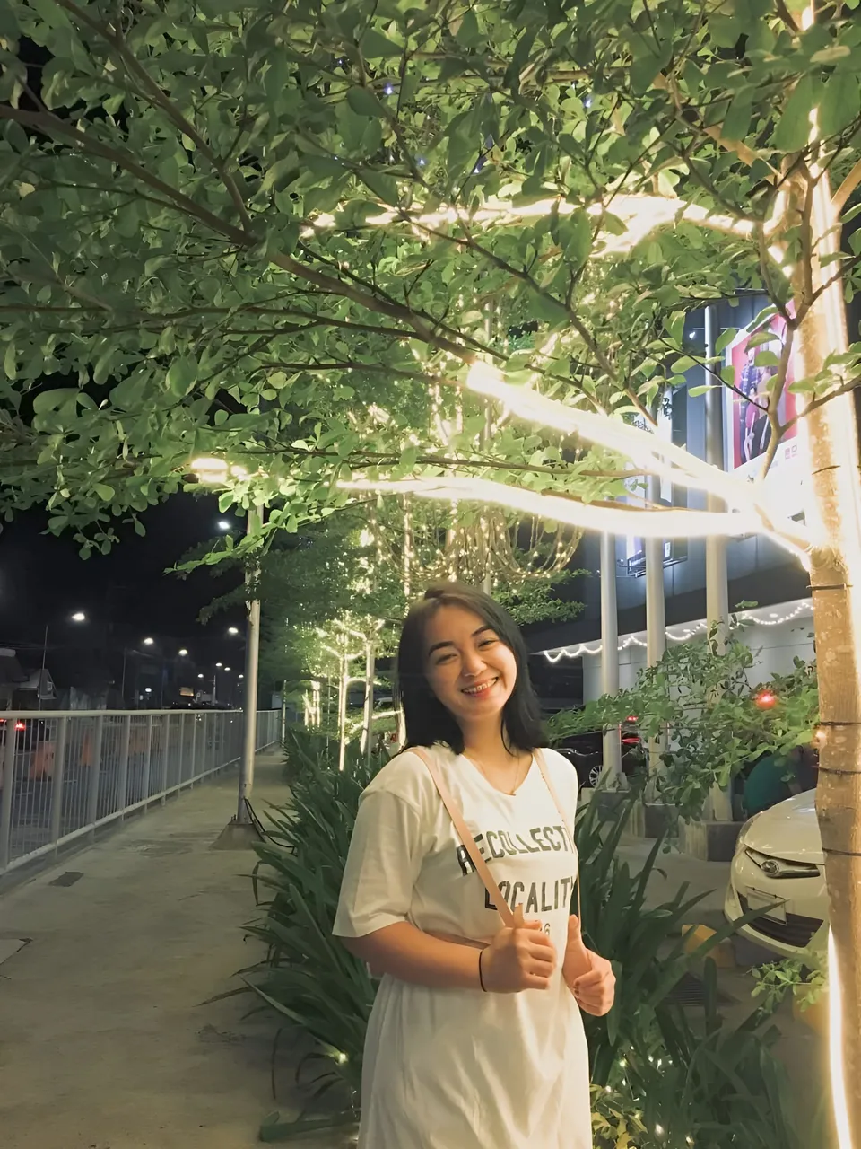Sakura Keyema in white top standing under illuminated tree at night