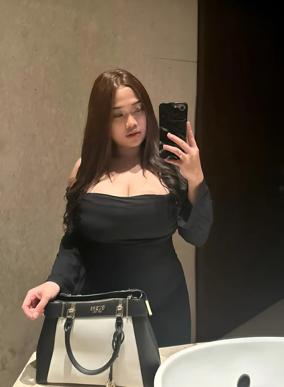 Serena Vale in black off-shoulder dress taking mirror selfie