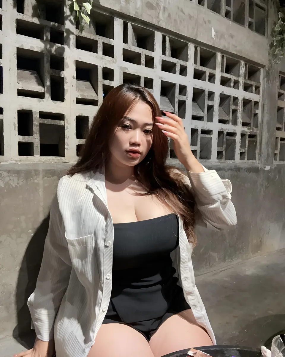 Serena Vale in white shirt and black top seated against concrete wall