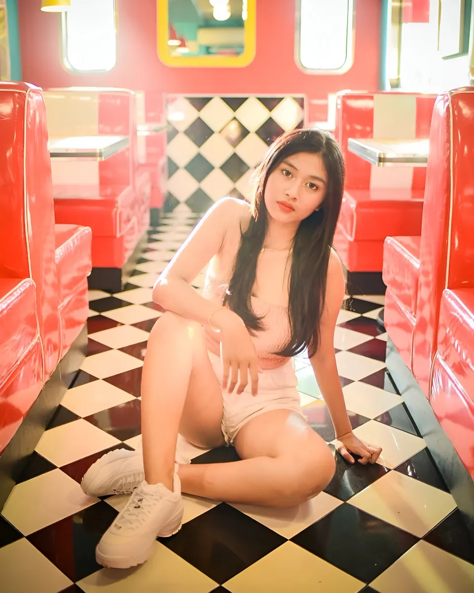 Sri Ayu Tarisa in pink top sitting on checkered floor