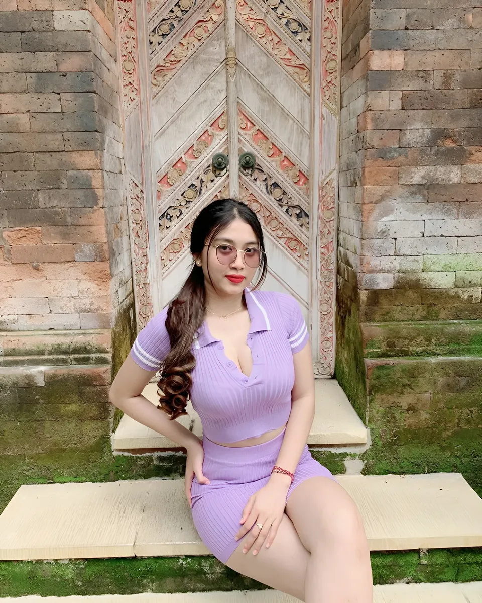 Sri Ayu Tarisa in purple ribbed outfit seated on bench outdoors